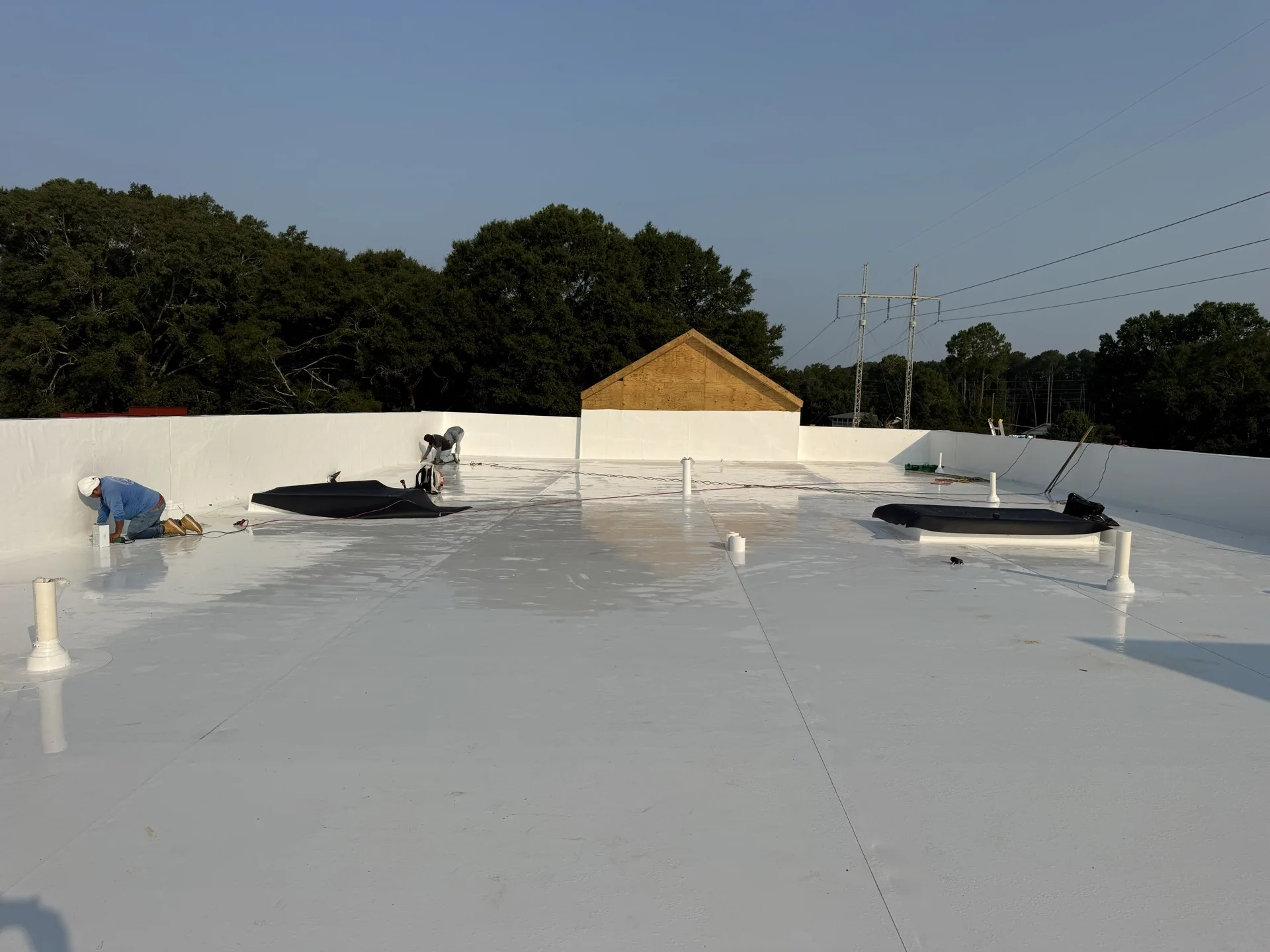 White single-ply field membrane and perimeter work during an active low-slope roof installation